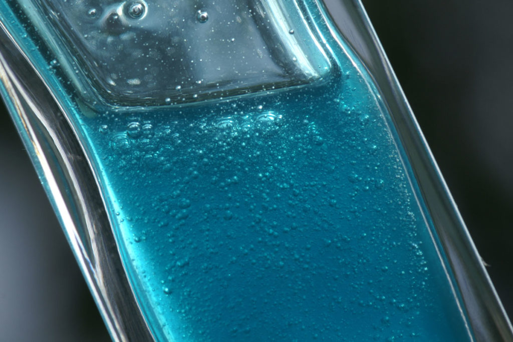 Blau eingefärbtes Duschgel in einer schmalen Glasflasche